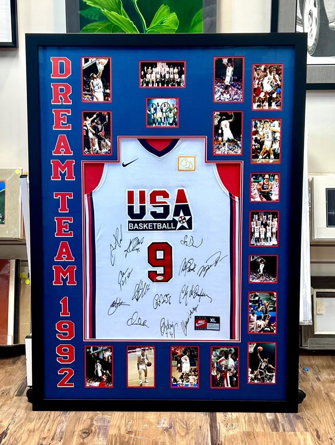 Two-story house with gray siding and garage doors, wet street reflects the evening sky.