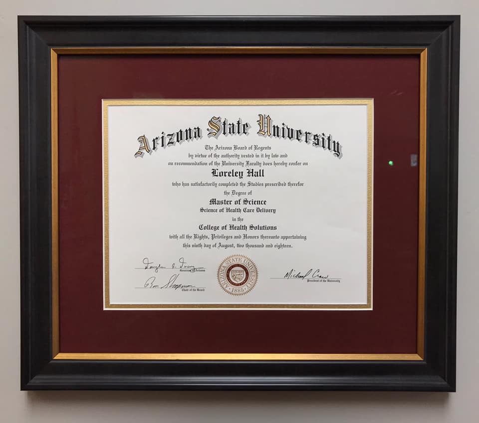 Two-story house with gray siding and garage doors, wet street reflects the evening sky.