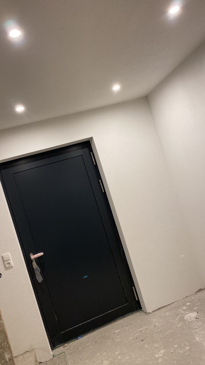 Eine schwarze Tür befindet sich in einem Raum mit weißen Wänden.