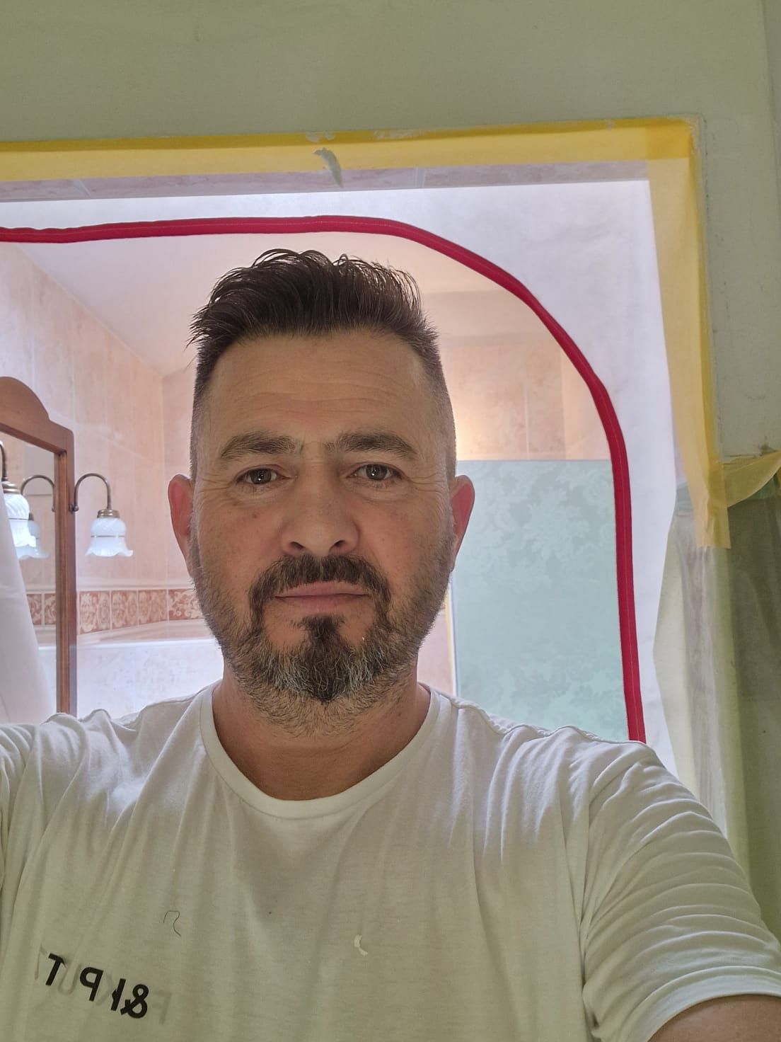 Ein Mann mit Bart macht in einem Badezimmer ein Selfie.