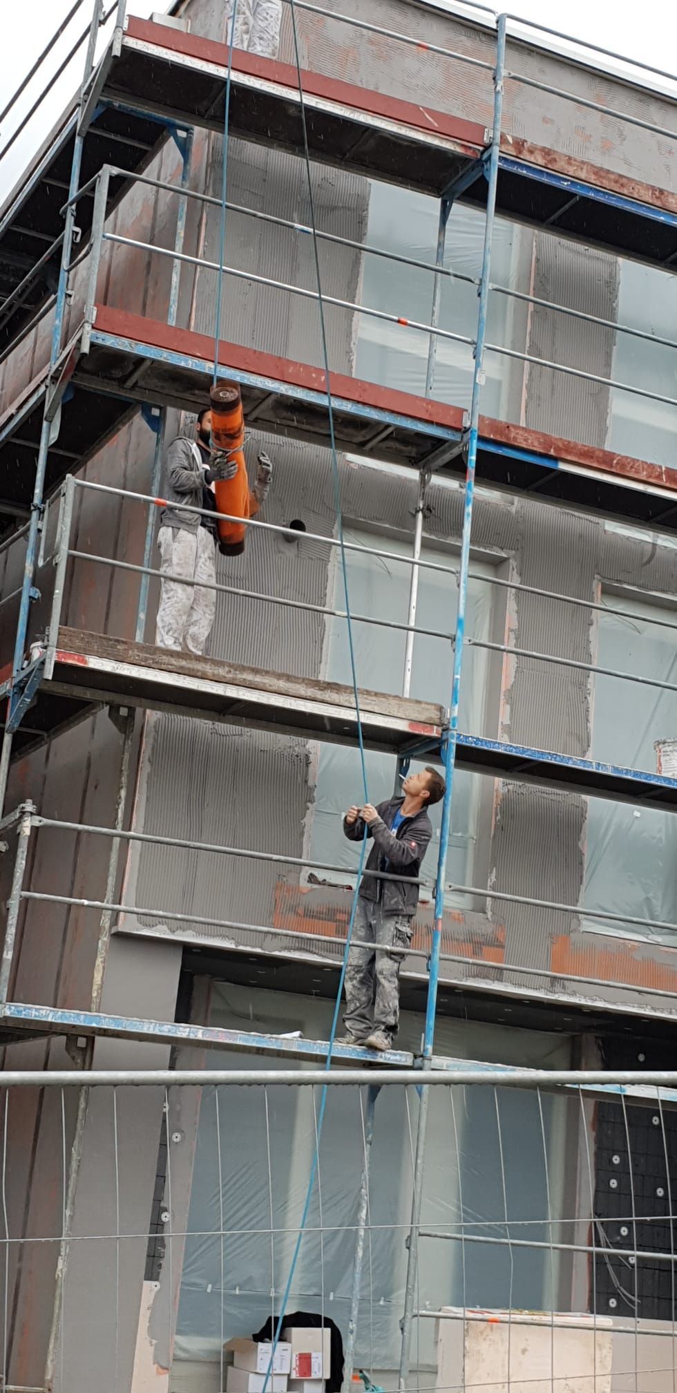 Ein Mann steht auf einem Gerüst an der Seite eines Gebäudes.