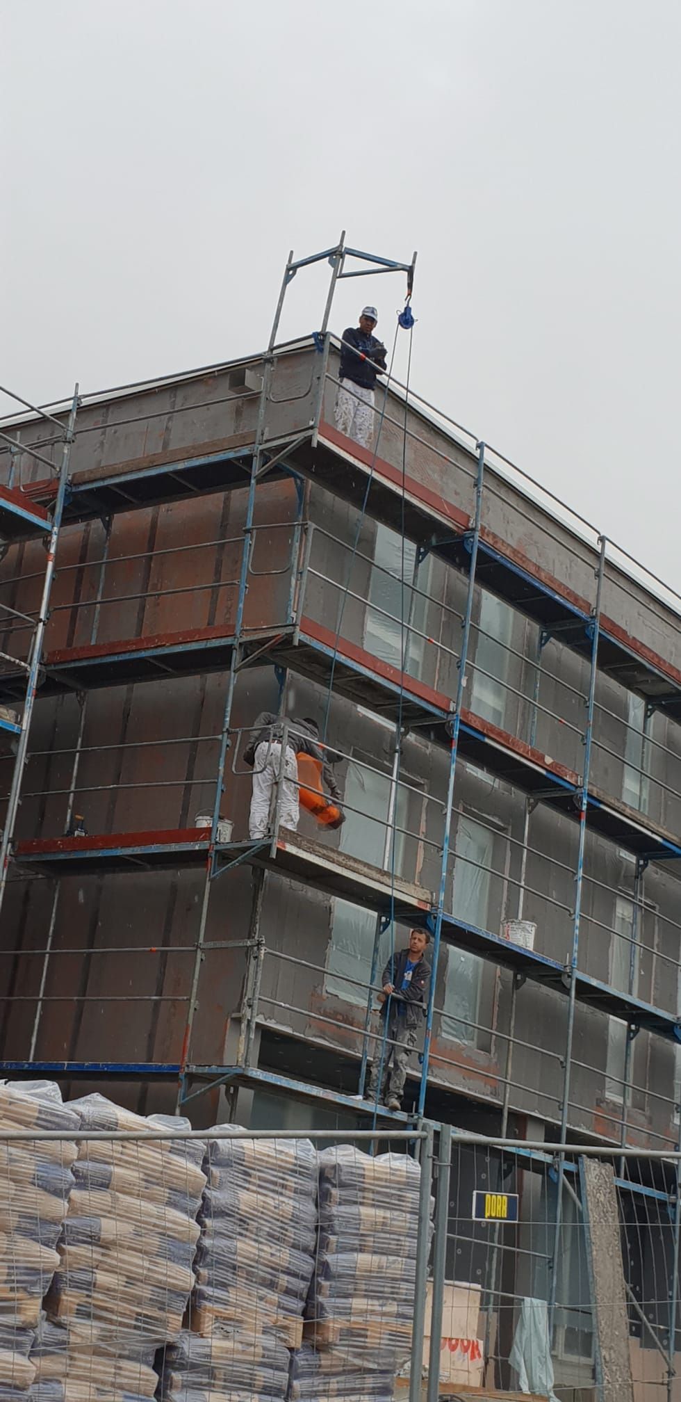 Ein Mann steht auf einem Gebäude, das mit einem Gerüst bedeckt ist.