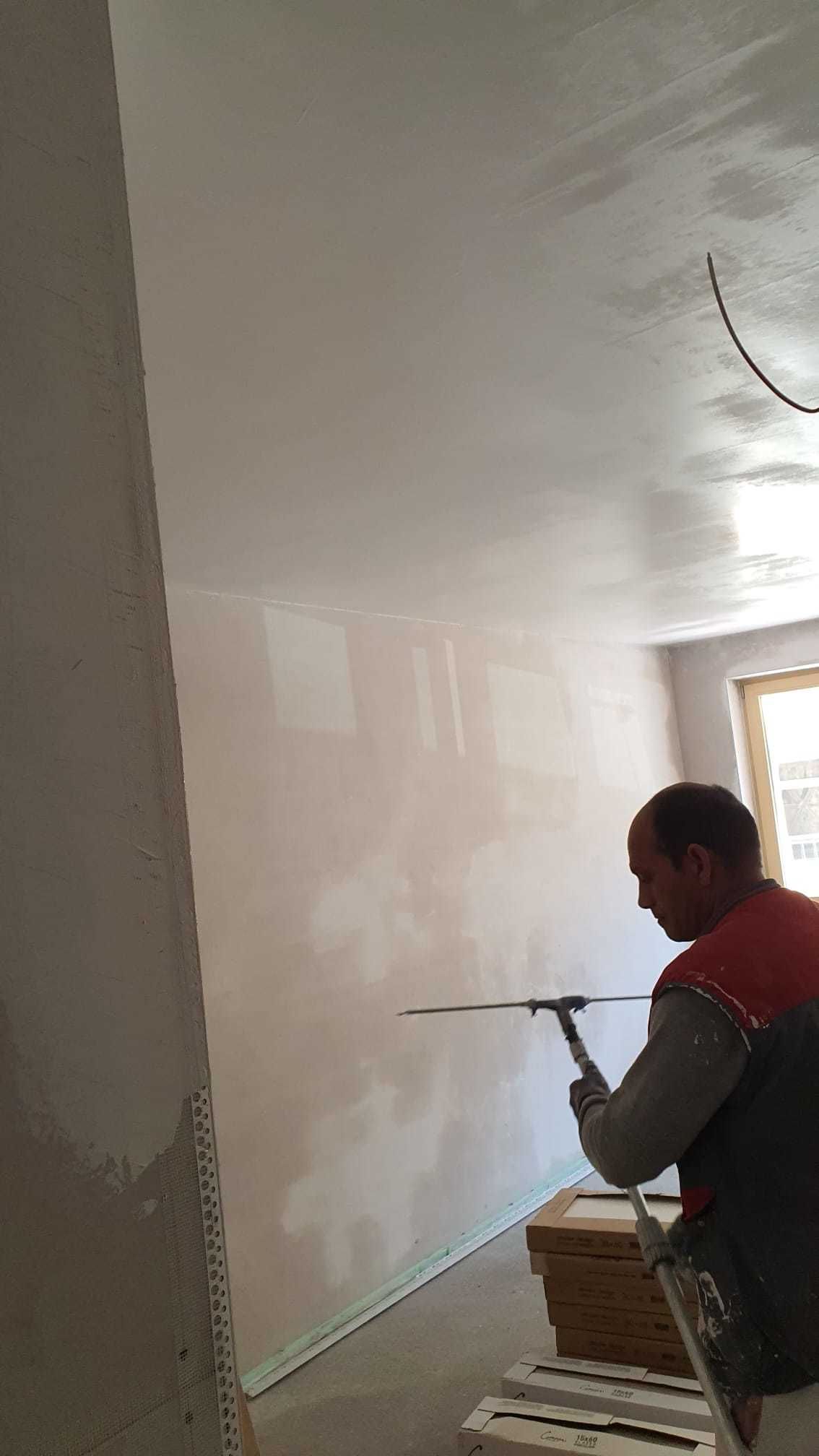 Ein Mann schlägt einen Nagel in eine Zimmerwand.