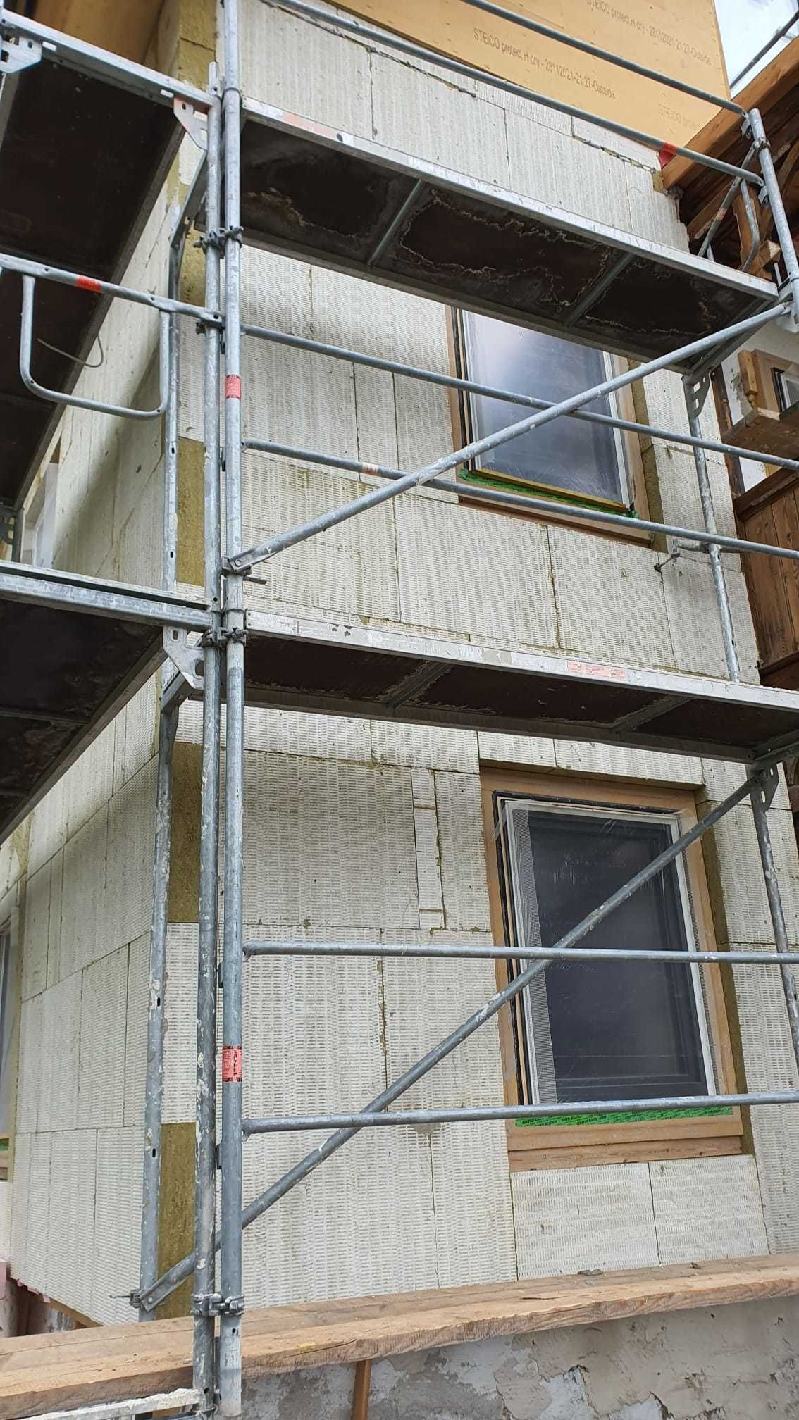 Ein im Bau befindliches Gebäude mit Gerüst darum und einem Fenster.