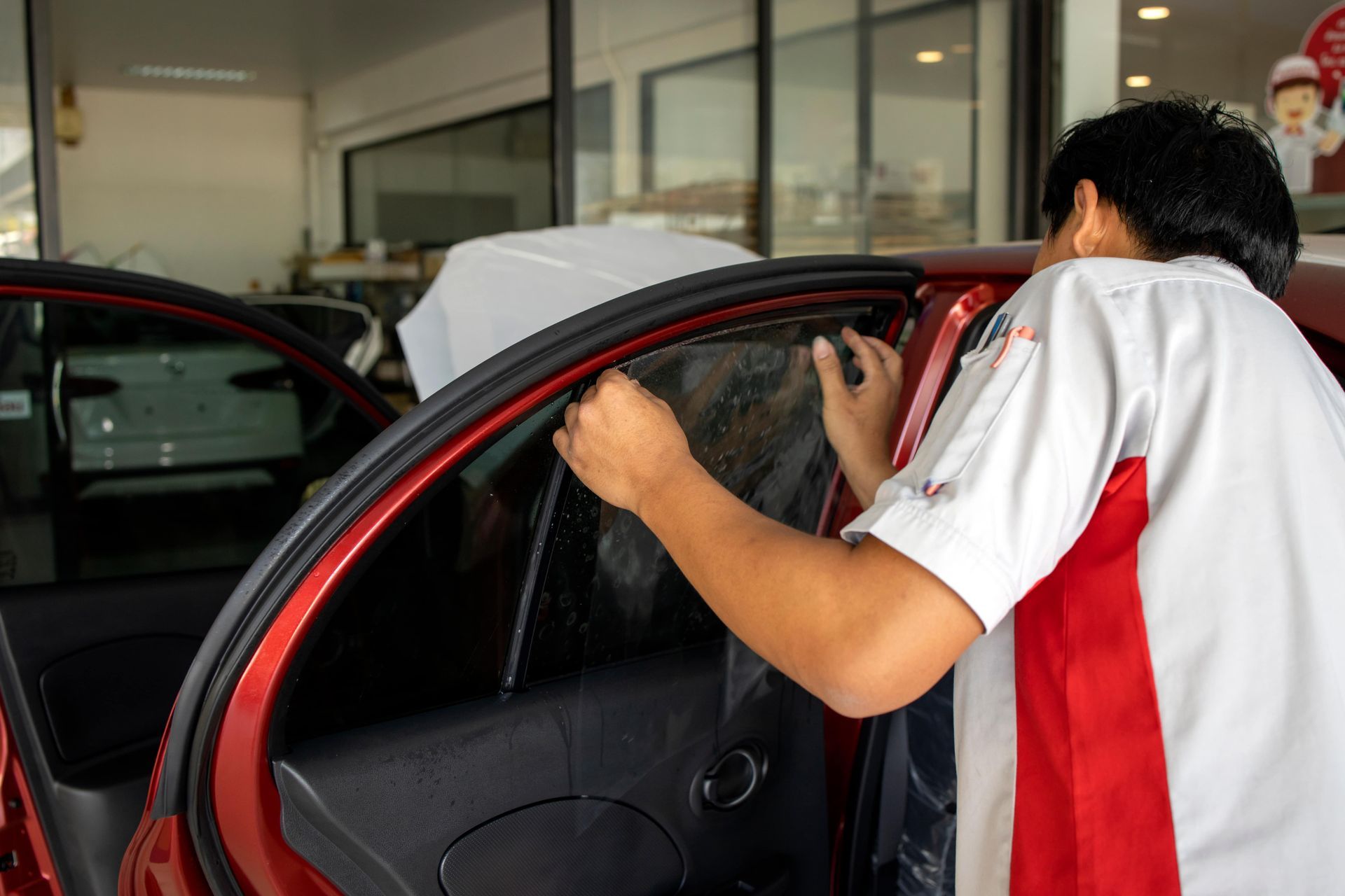 A person is polishing the headlights of a car.