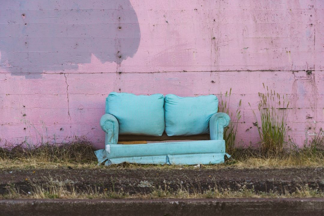 A blue couch is sitting in front of a pink wall.