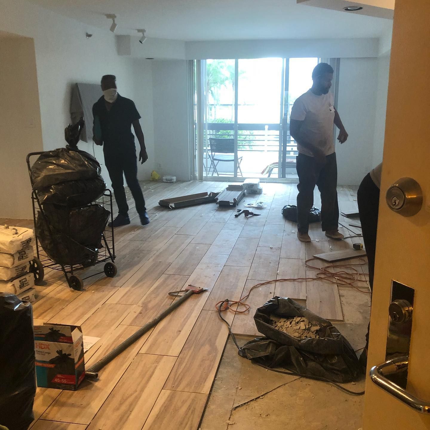 Electrician in hardhat and safety vest inspecting electrical panel, taking notes.