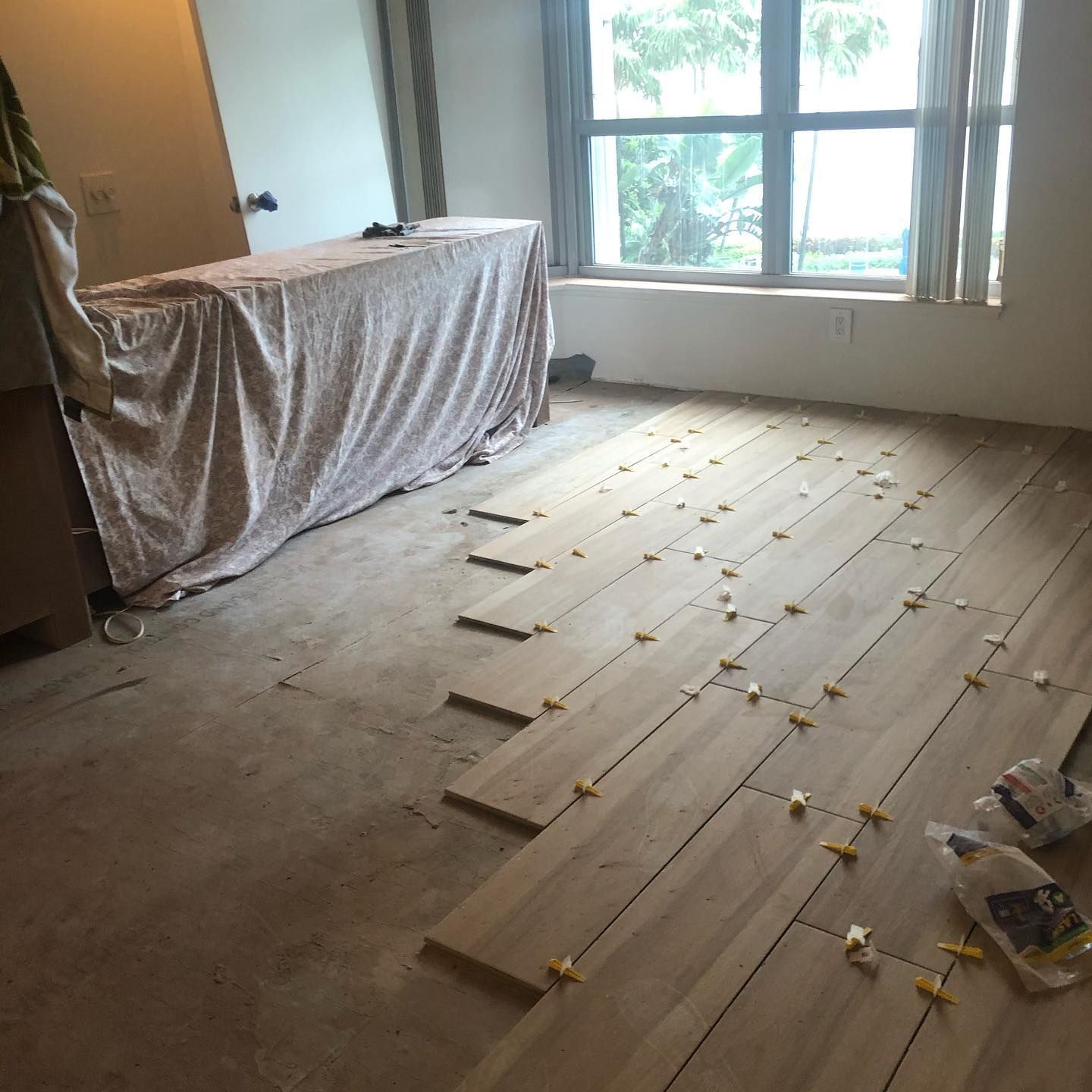 Room with unfinished wooden plank flooring, window, and covered counter.