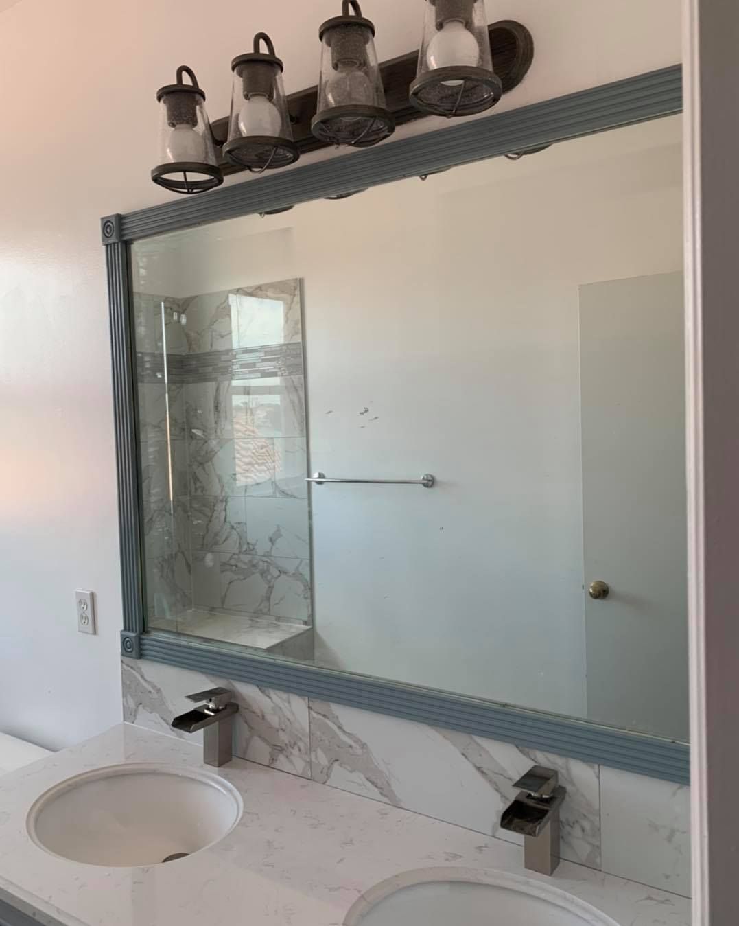 Bathroom with a large mirror above a double sink vanity. Decorative lighting fixtures are above the mirror.
