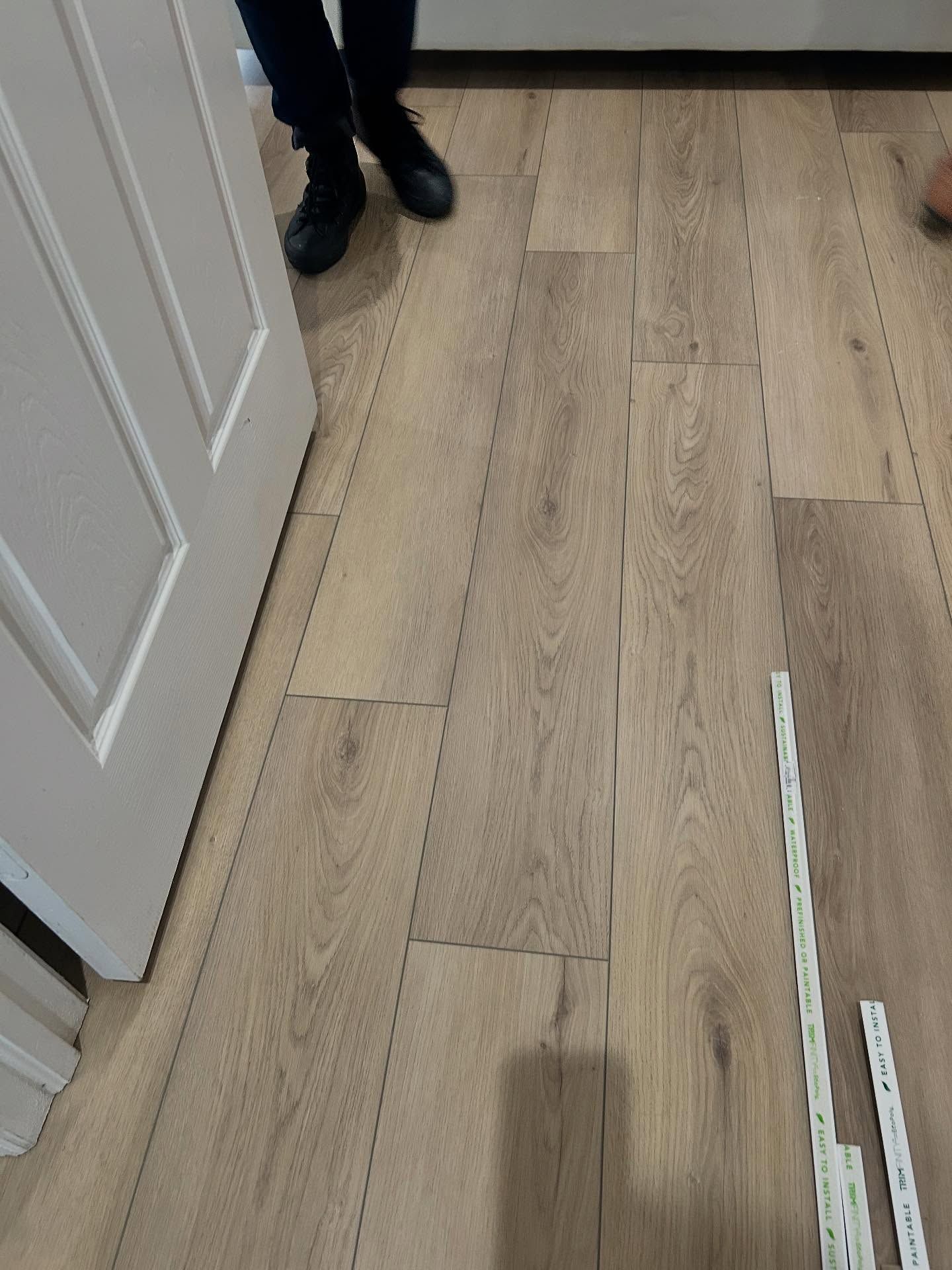 Wooden floorboards, with a door and feet visible.