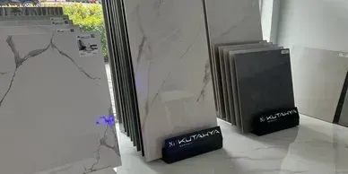 Display of ceramic tiles with marble-like patterns. Some tiles are grey. Tiles are propped up in a showroom.