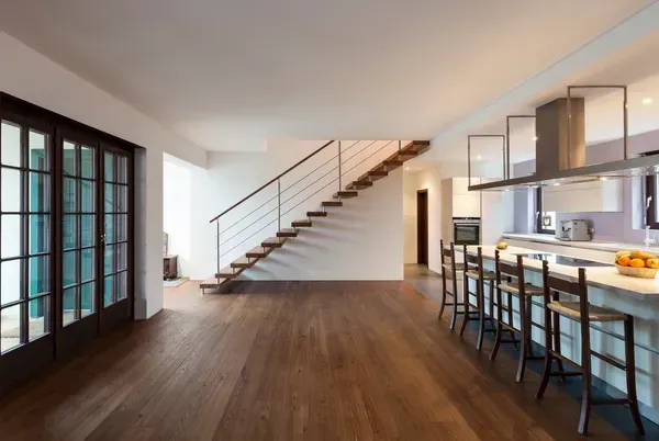 Empty modern home interior with wood floors, staircase, and kitchen island.