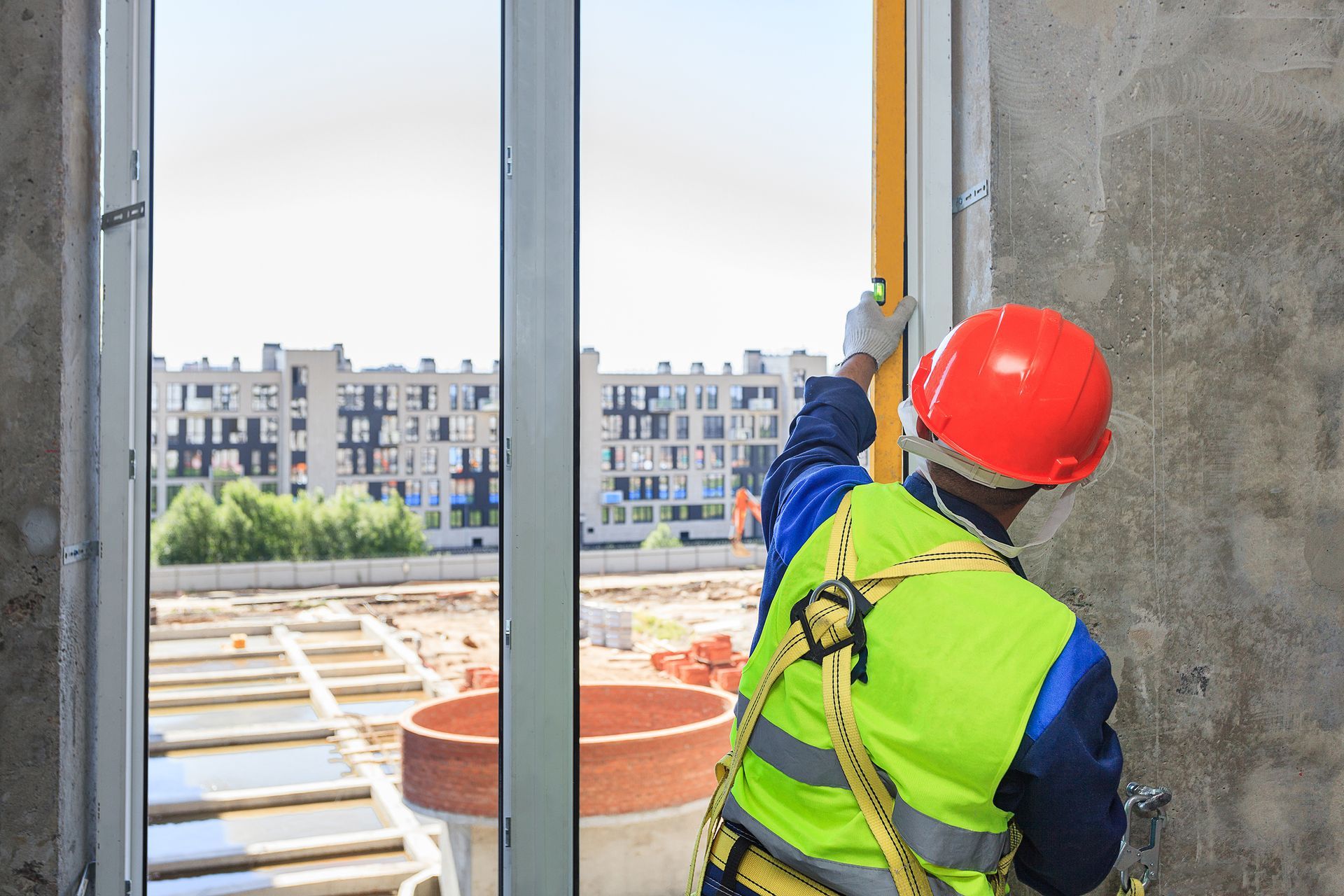 A worker in an orange helmet installs a double-glazed window in a new house.