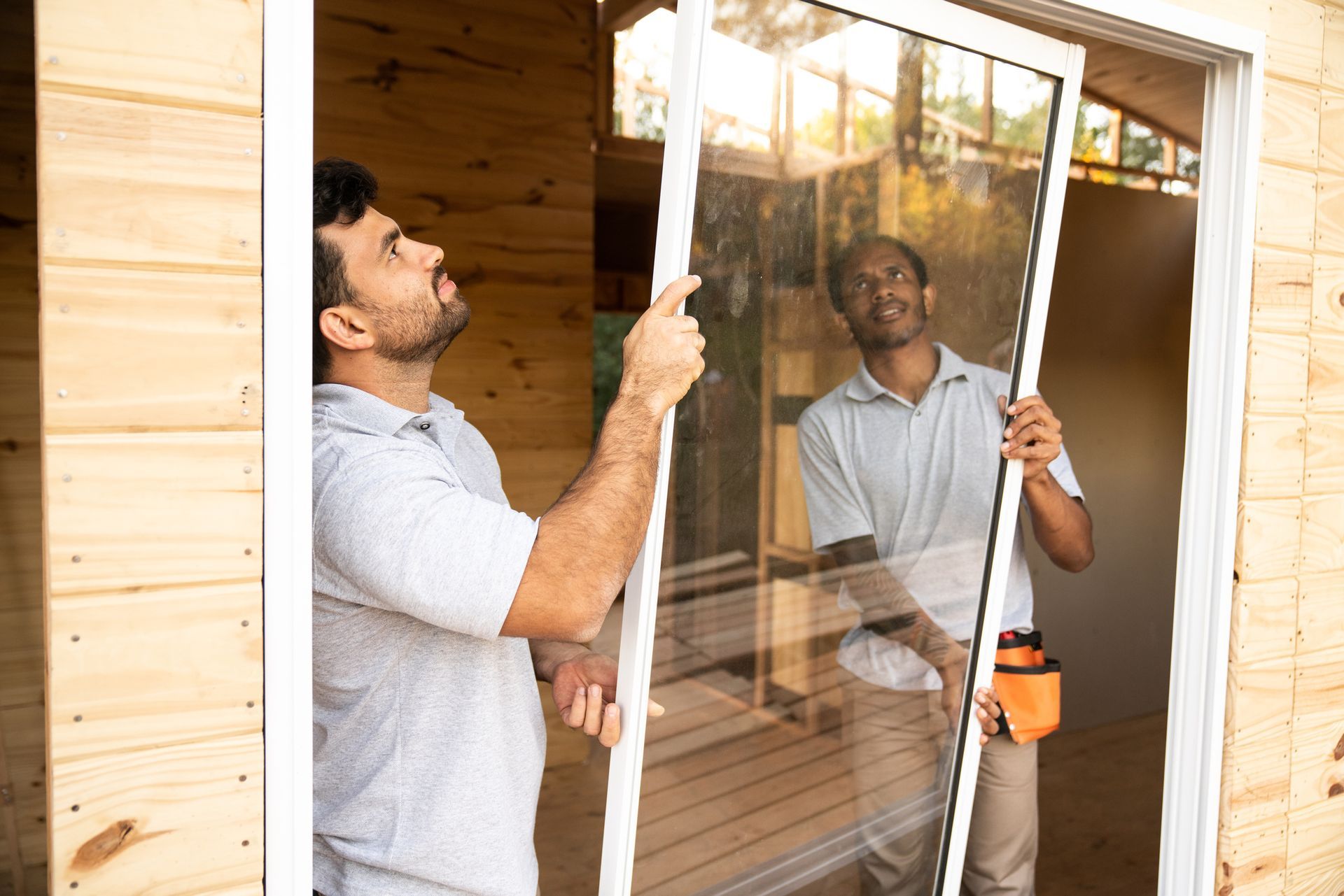 Construction workers installing windows on a   house, showcasing local window replacement services.