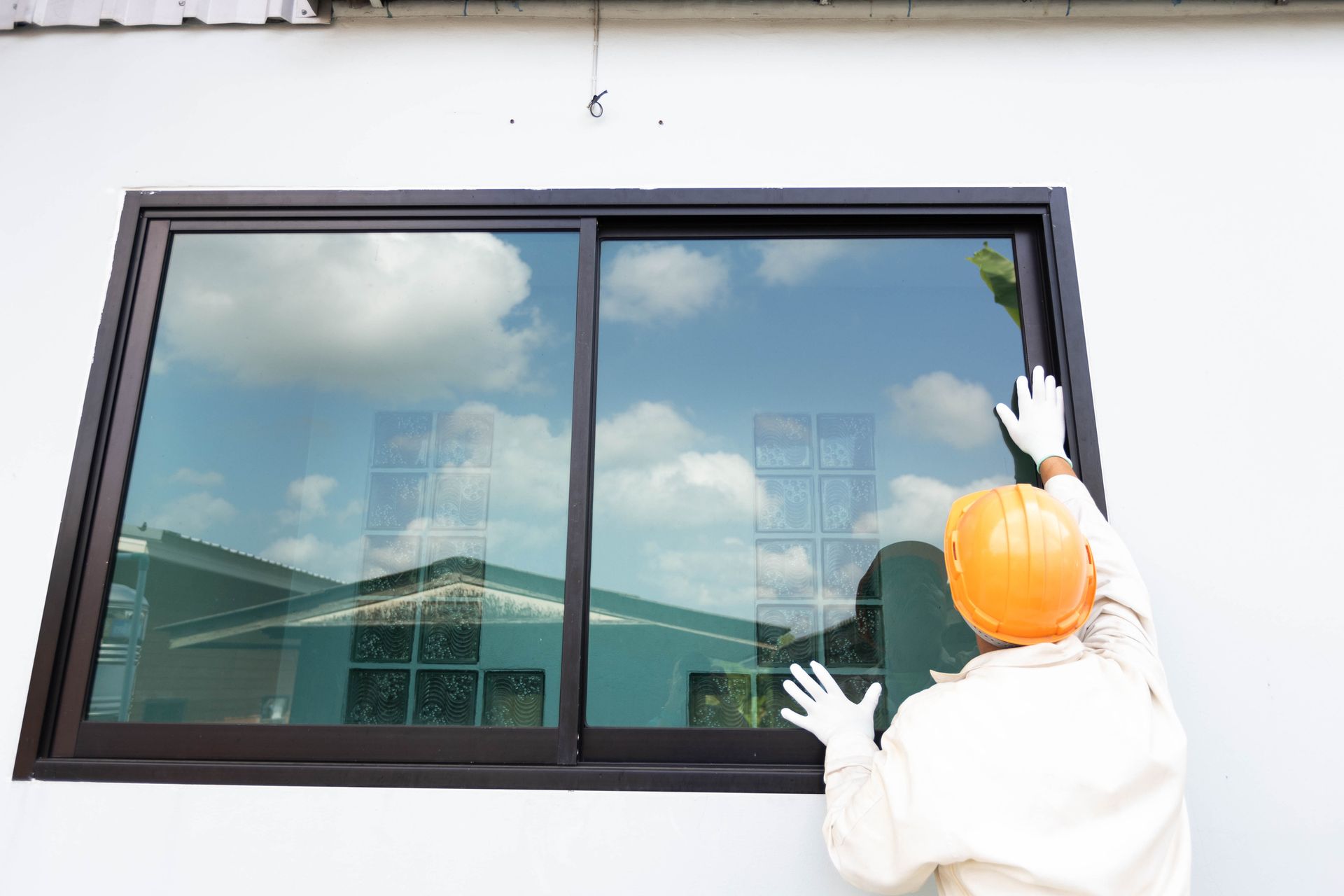 A glazier completing a window replacement at a residential property. A glazier completing a window replacement at a residential property.
