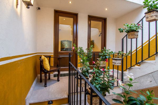 Un balcón con una silla y escaleras que conducen a una casa.