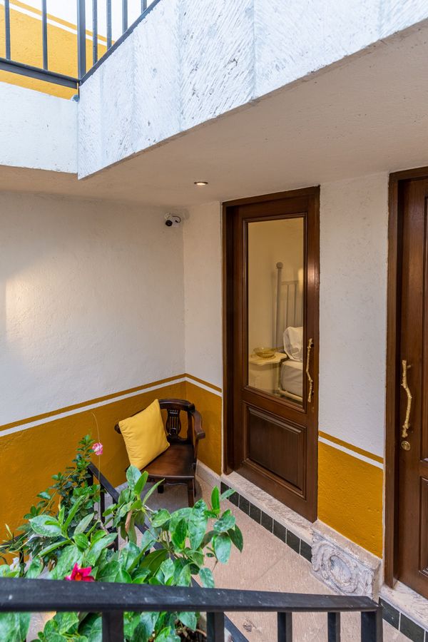Un balcón con una silla y una almohada amarilla delante de una puerta.