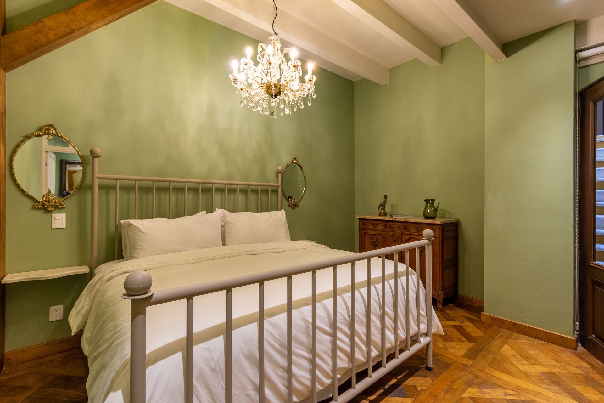 Un dormitorio con cama, tocador, espejo y lámpara de araña.