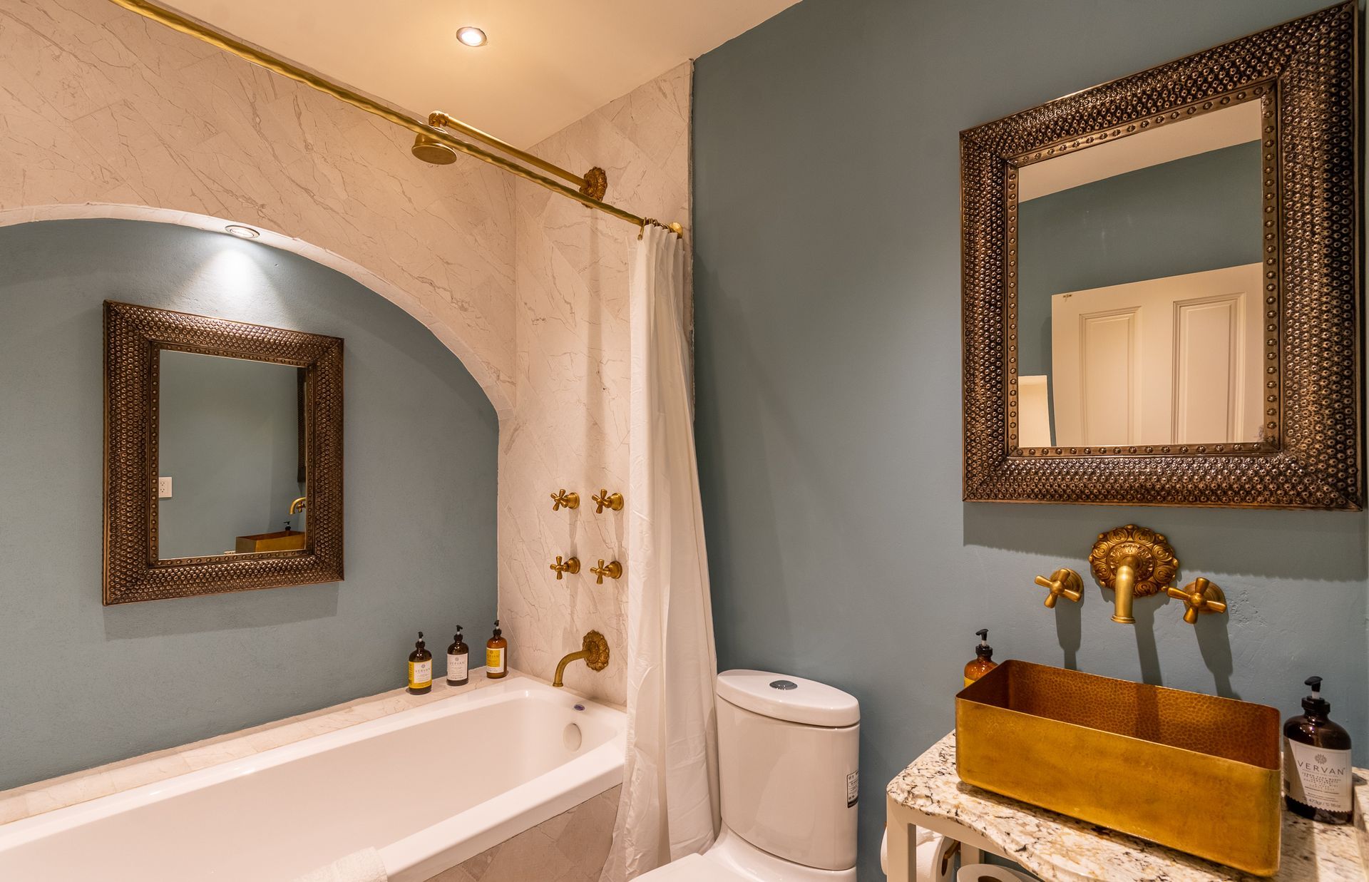Un baño con bañera, inodoro, lavabo y espejo.