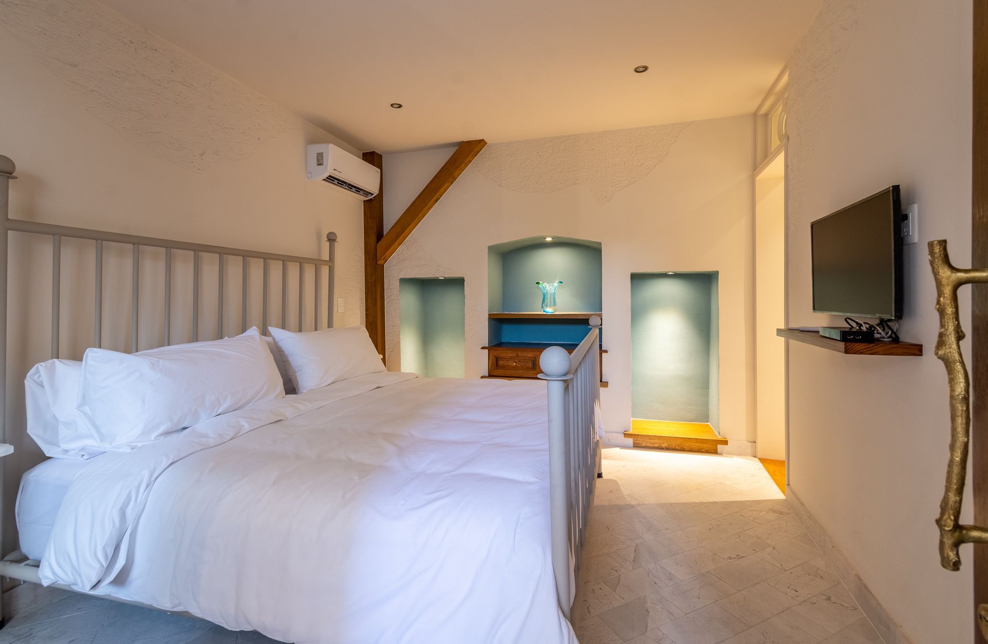 Un dormitorio con una cama y un televisor en la pared.
