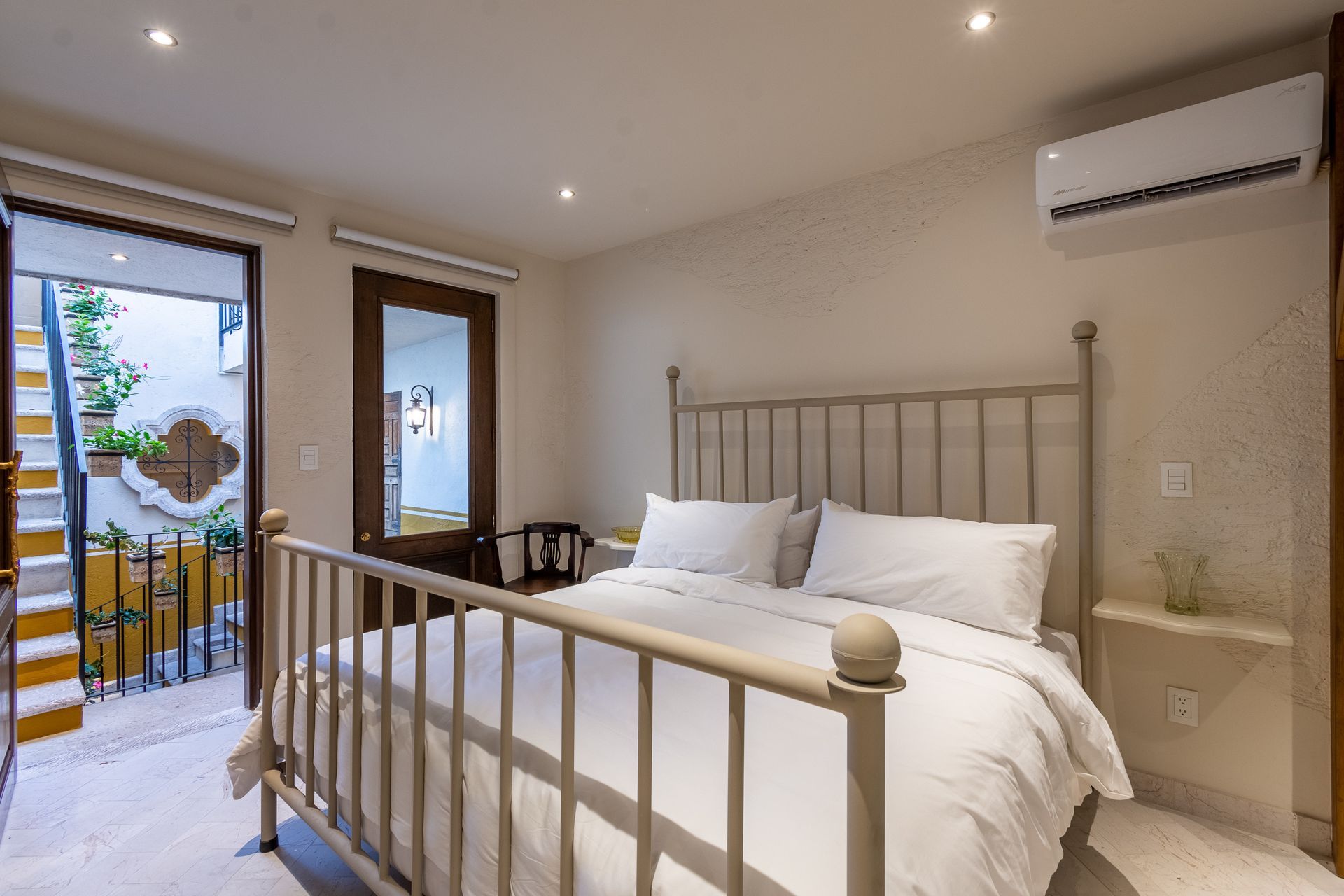 Un dormitorio con una cama, aire acondicionado y escaleras que conducen a un balcón.