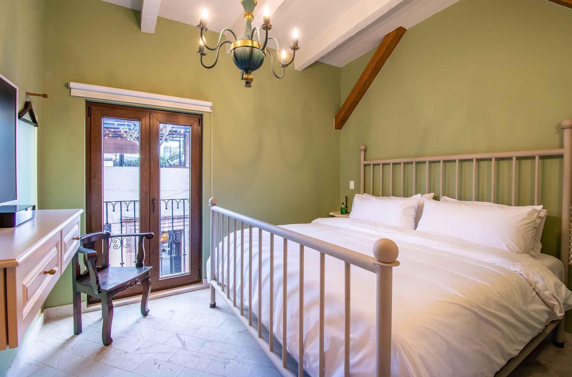 Un dormitorio con una cama, silla, escritorio y televisión.