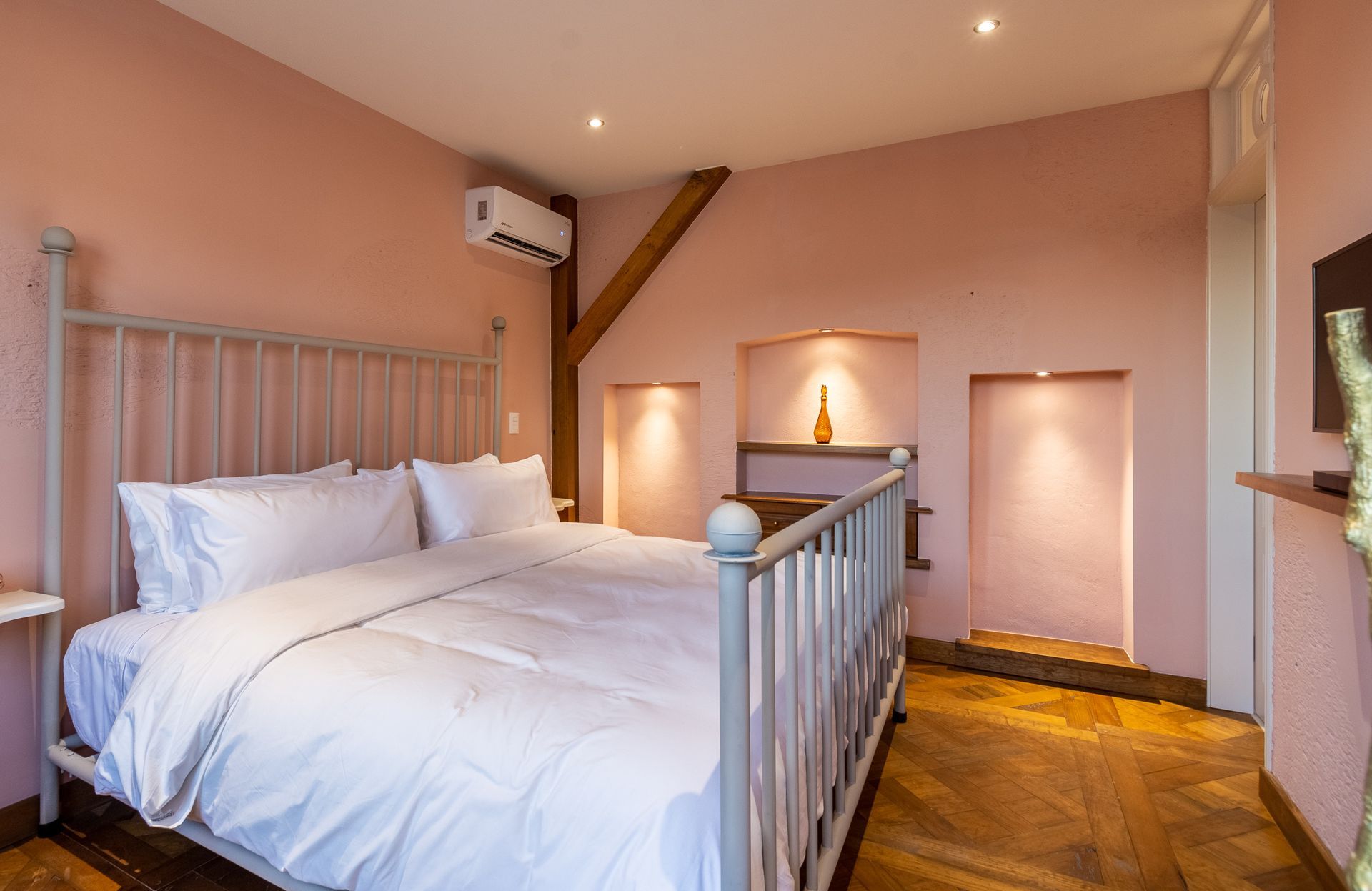 Un dormitorio con paredes rosas y una cama con sábanas blancas.