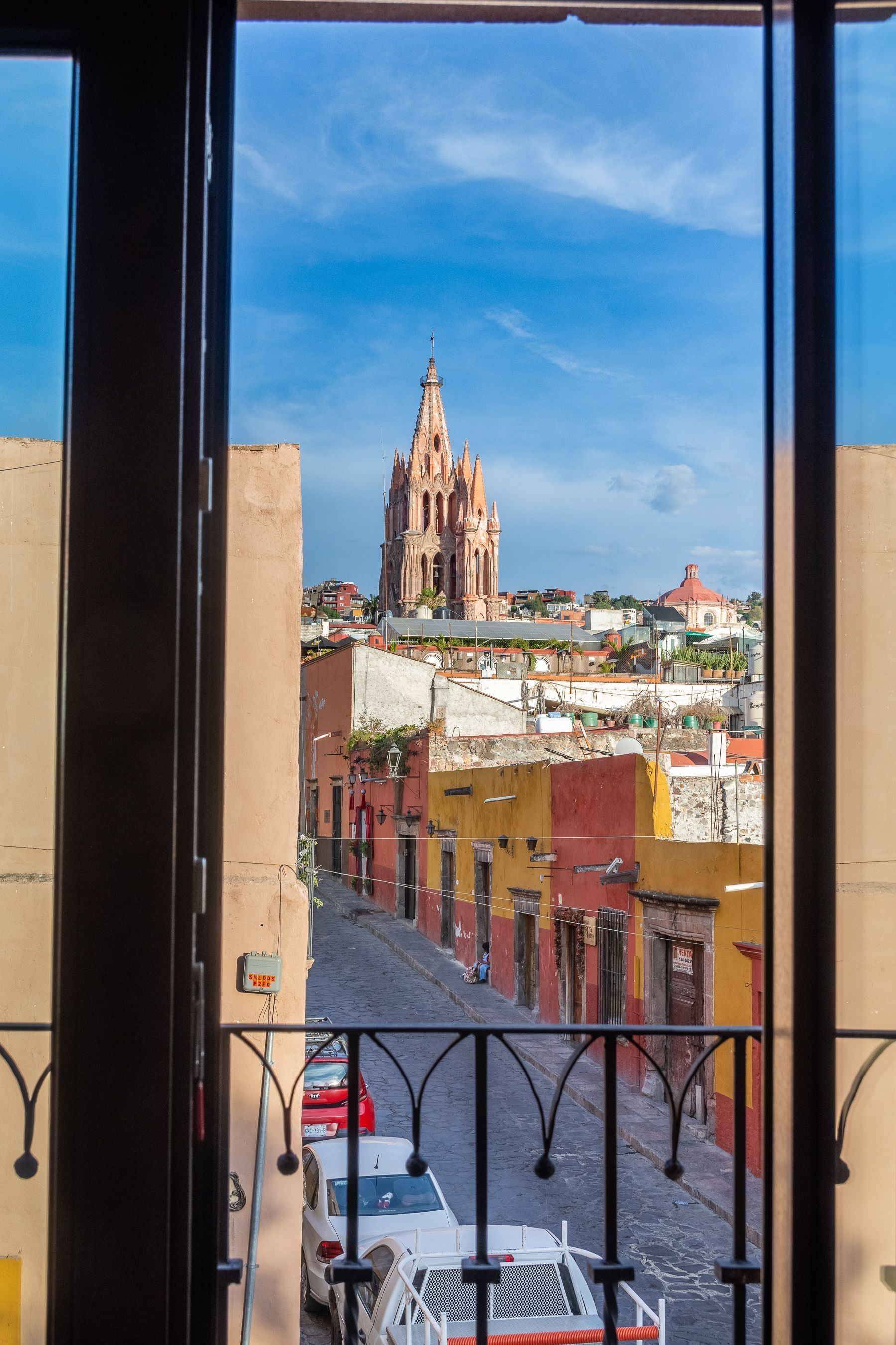 Una vista de una ciudad desde un balcón con una iglesia al fondo.