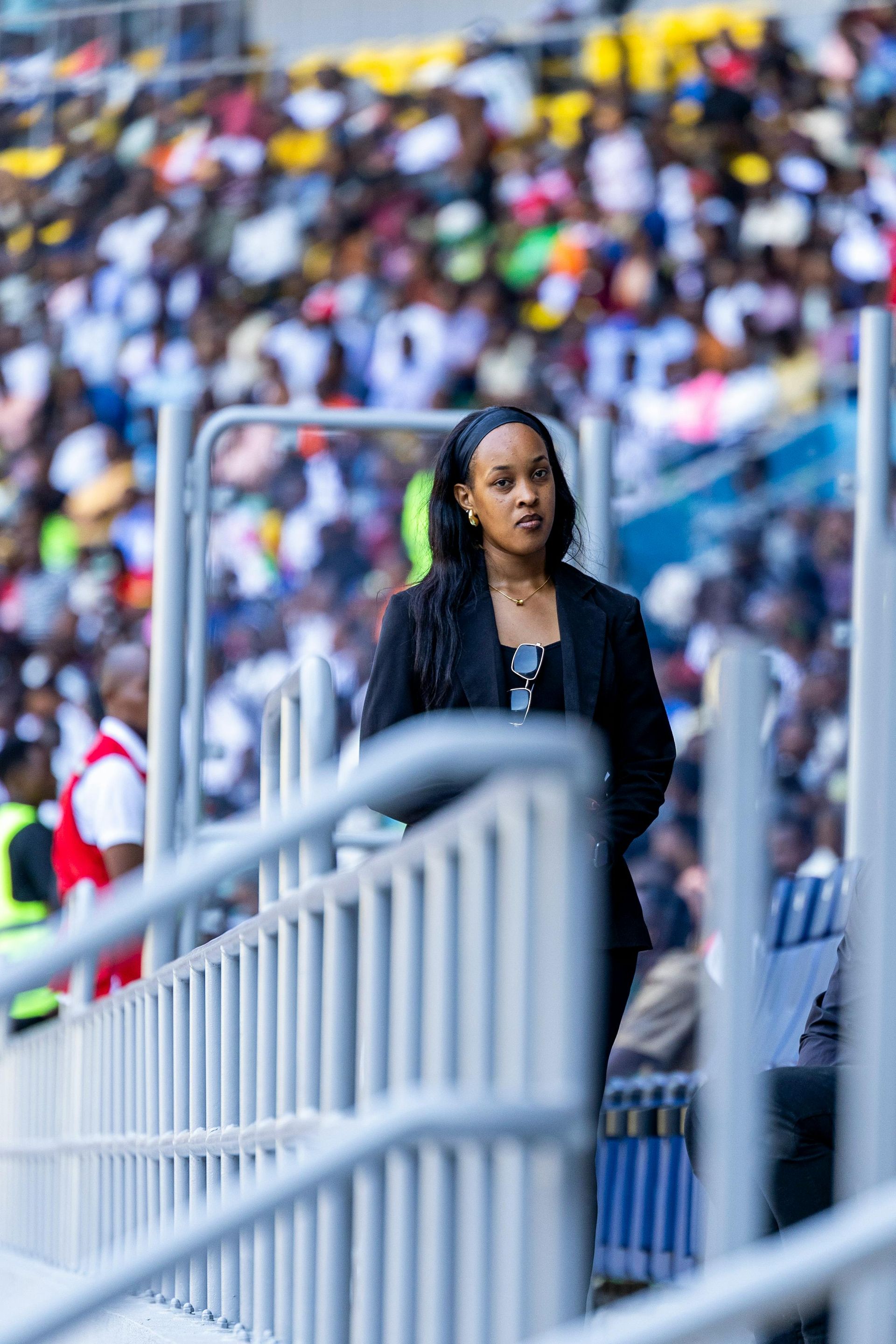 Una mujer está parada en un estadio detrás de una valla.