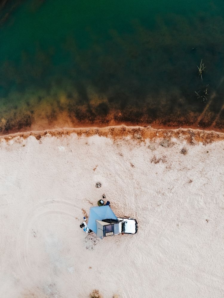 A Camper Van is Parked on a Grassy Hill Overlooking the Ocean — Murgon Auto Parts & Outdoors in Murgon, QLD
