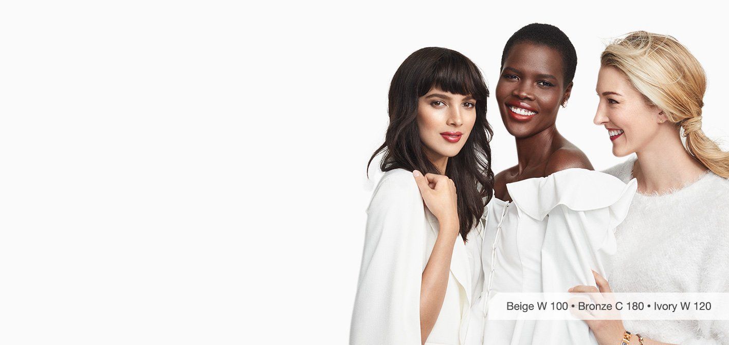 Three women are standing next to each other in white dresses.