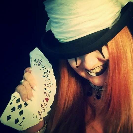 A woman in a top hat is holding a fan of playing cards, Belladonna LaVeau.