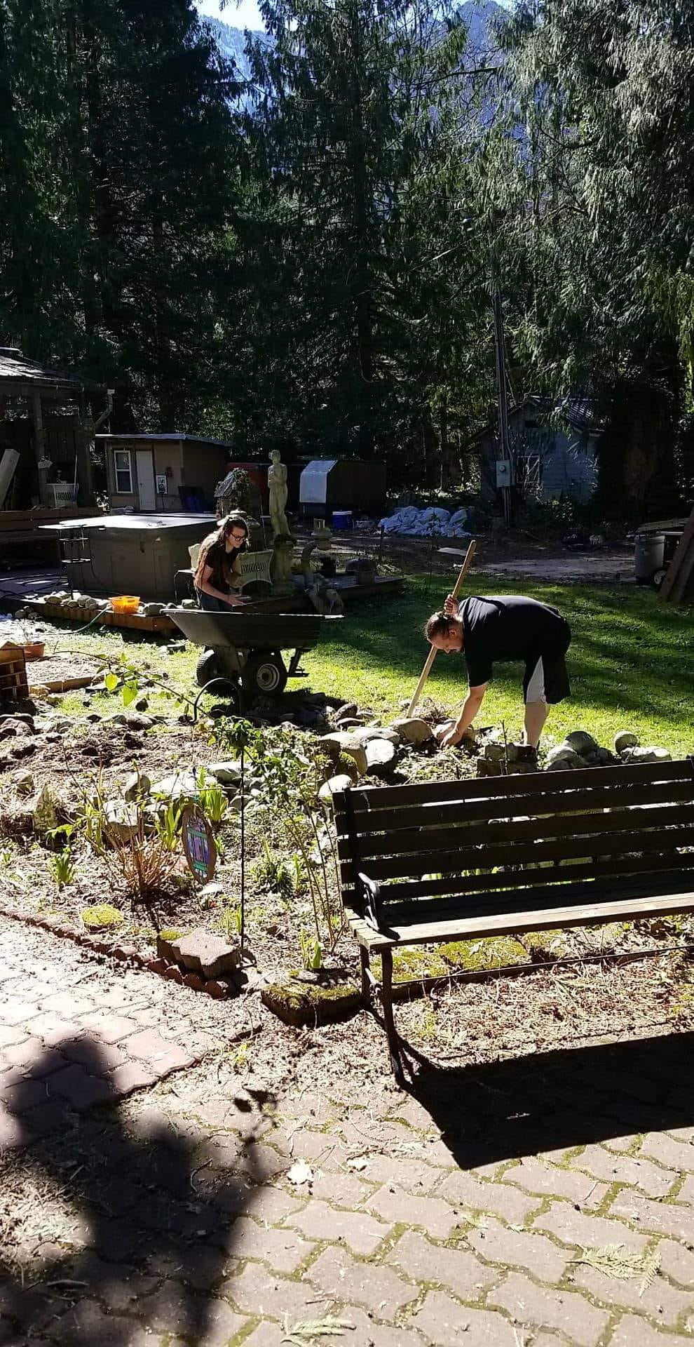 A man is working in a garden next to a bench.