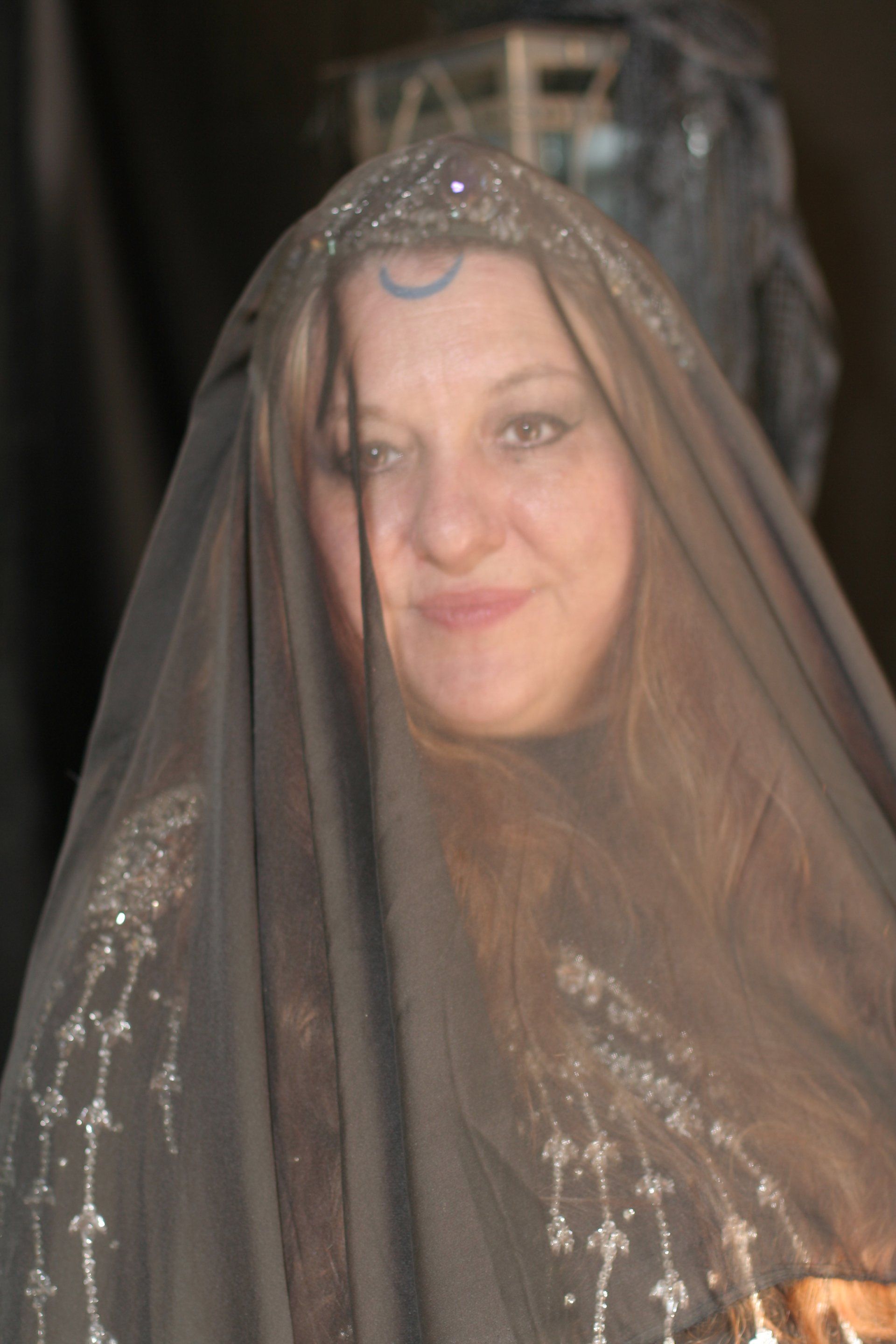 A woman with a veil on her head is smiling, Belladonna LaVeau.