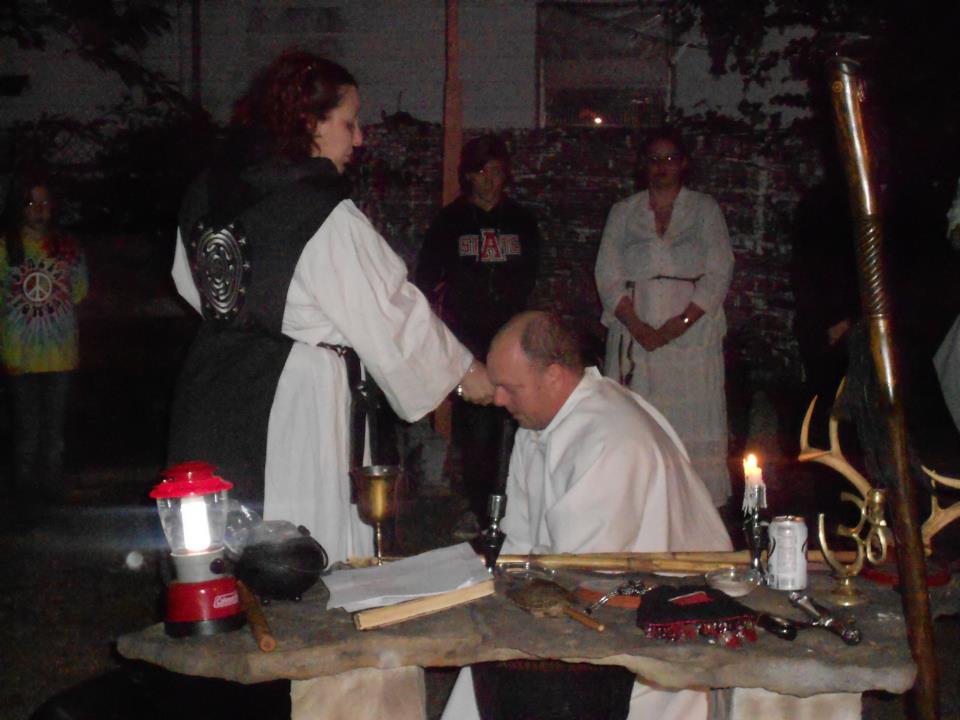 A group of people are gathered around a table with candles and a lantern