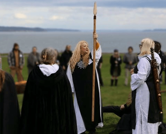 A group of people are standing in a field holding sticks.