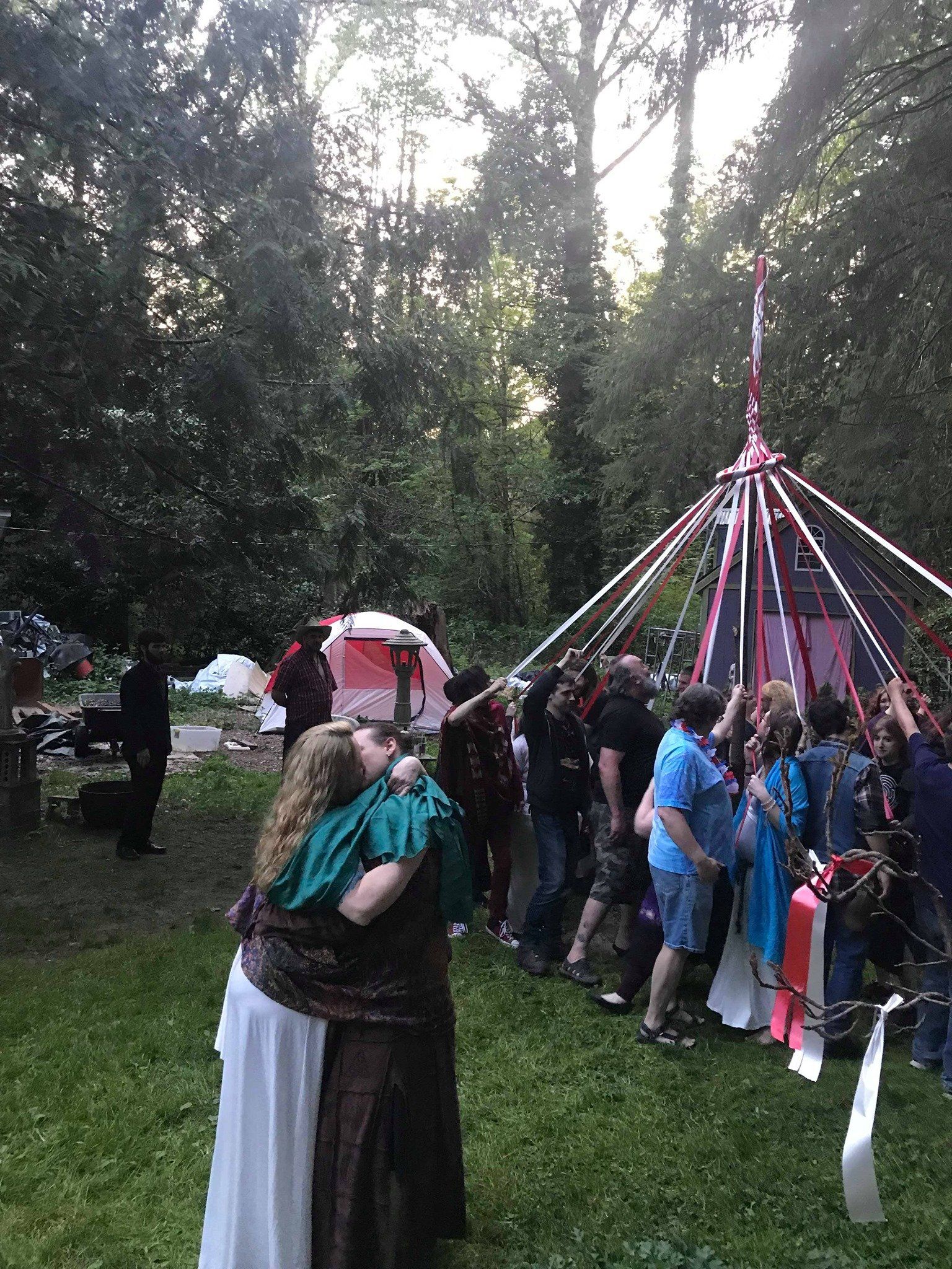 A group of people are standing in a field in front of a tent.