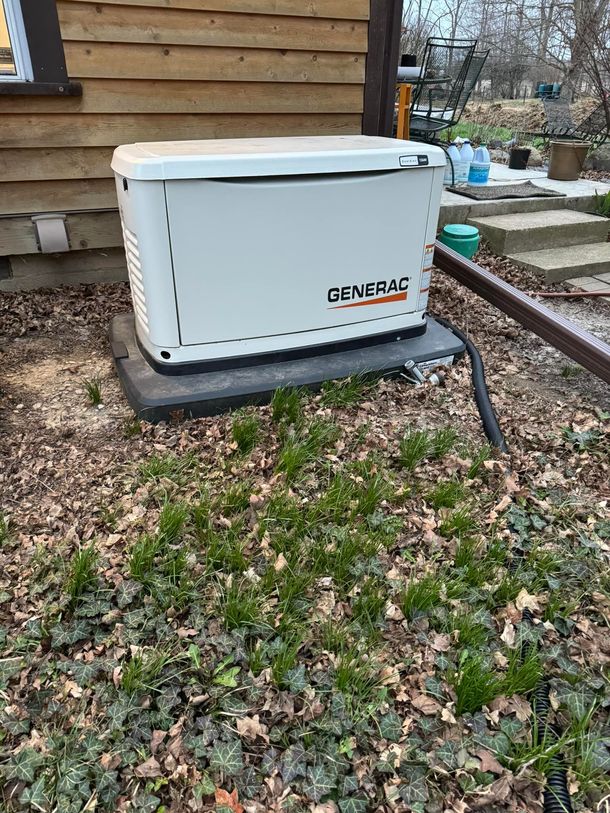 A generator is sitting in the grass in front of a house.