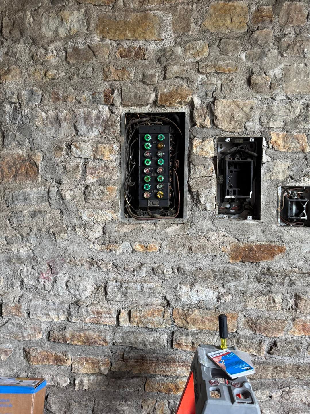 A brick wall with two electrical boxes in it.