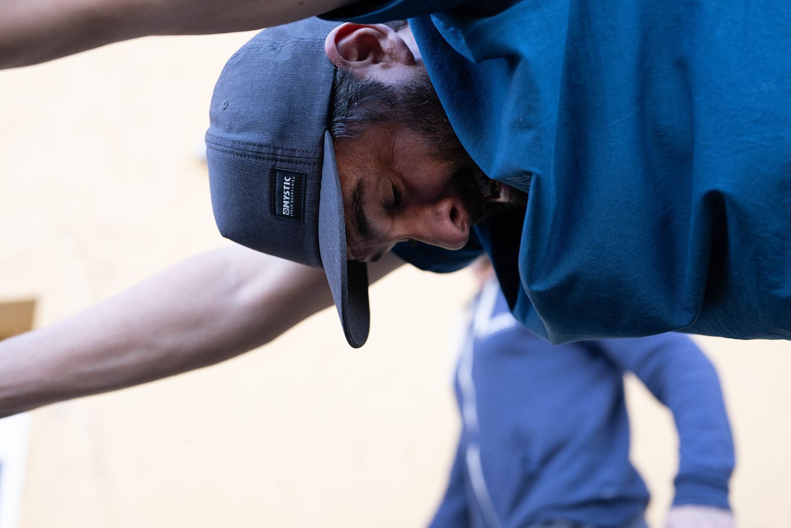 A man wearing a hat is doing a handstand upside down.
