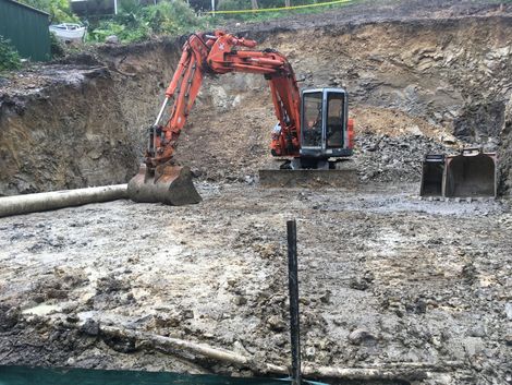 An orange excavator in a muddy excavation pit. — Lakesway Earthmoving in Charlotte Bay, NSW