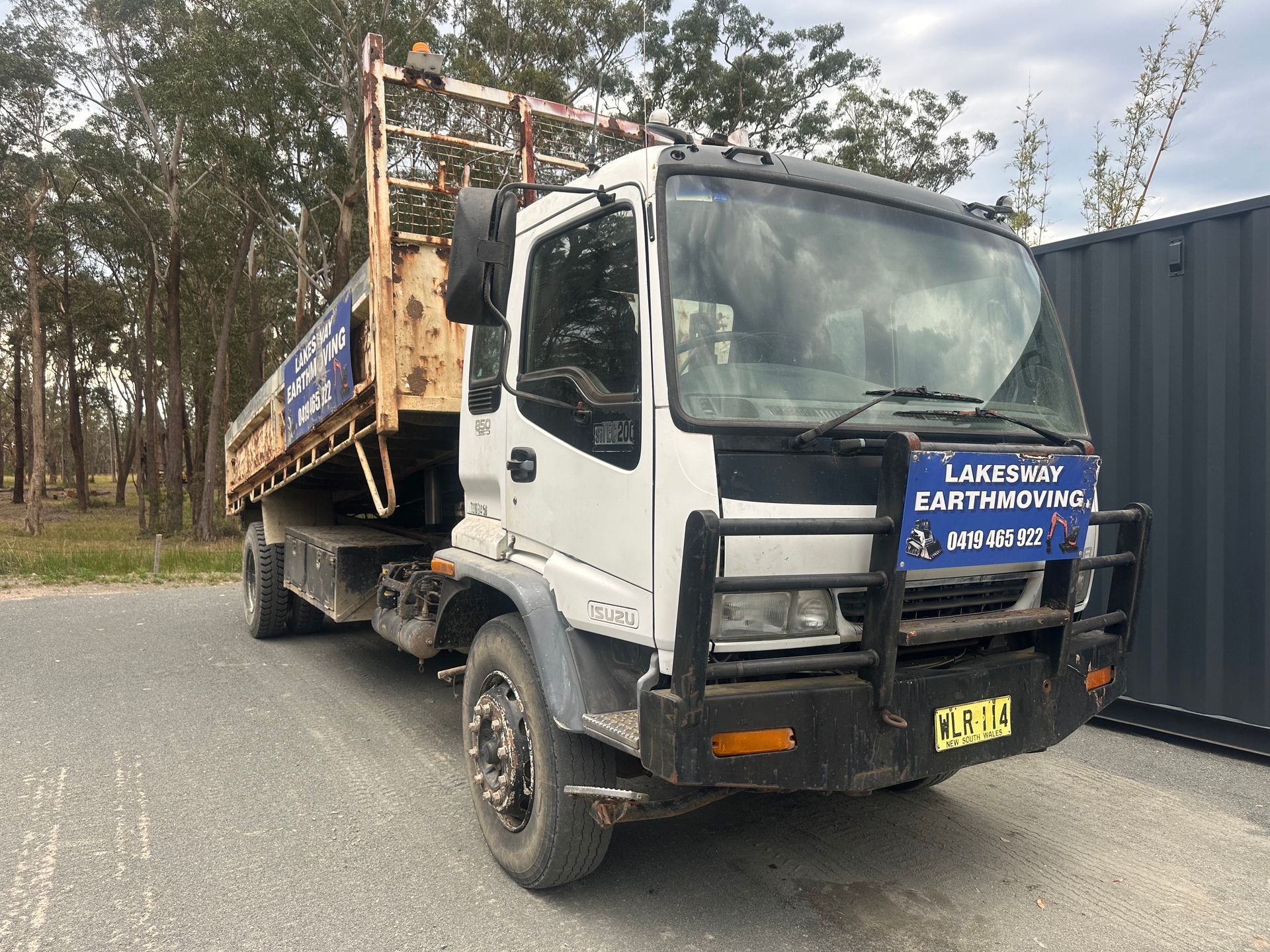 White flatbed truck with blue signage, parked outdoors. — Lakesway Earthmoving in Charlotte Bay, NSW