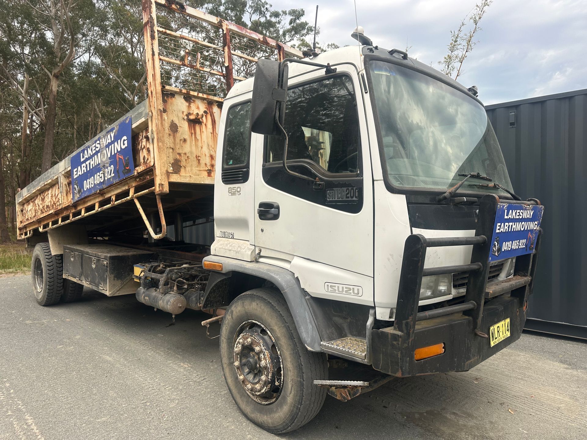 White Isuzu truck with a flatbed, parked outdoors. — Lakesway Earthmoving in Charlotte Bay, NSW