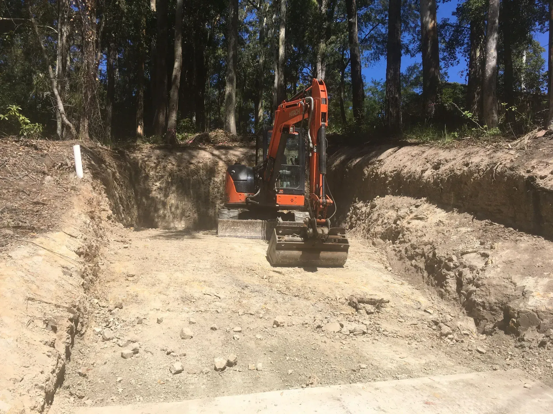 Orange excavator in a dirt trench, trees in the background. — Lakesway Earthmoving in Bulahdelah, NSW