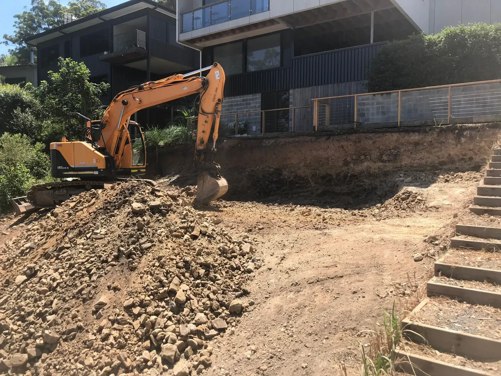 A Large Excavator is Sitting on Top of a Dirt Field — Lakesway Earthmoving in Charlotte Bay, NSW