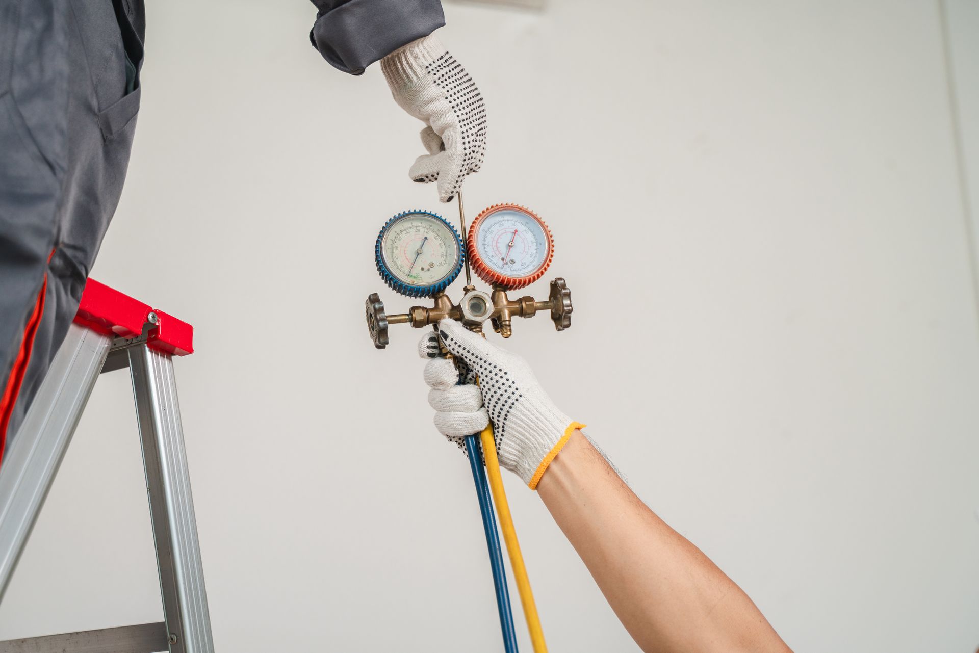 Two people using gauges to service air conditioning unit.