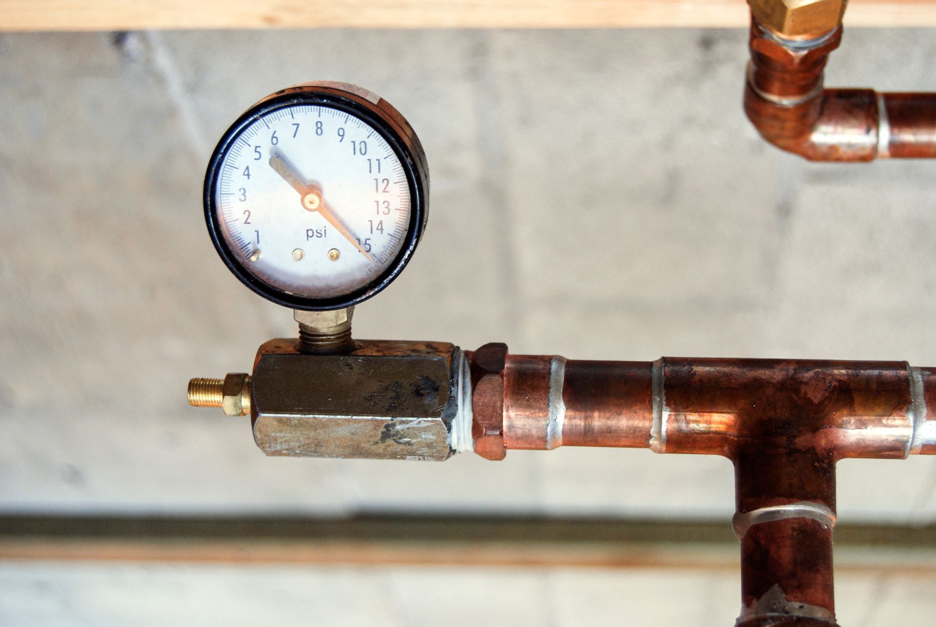 Pressure gauge attached to copper pipes, reading around 10 psi.