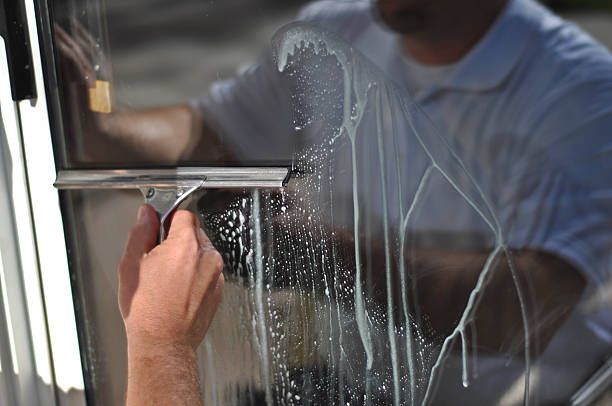 A man is cleaning a window with a squeegee.