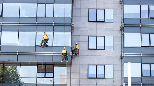 Three men are cleaning the windows of a tall building.