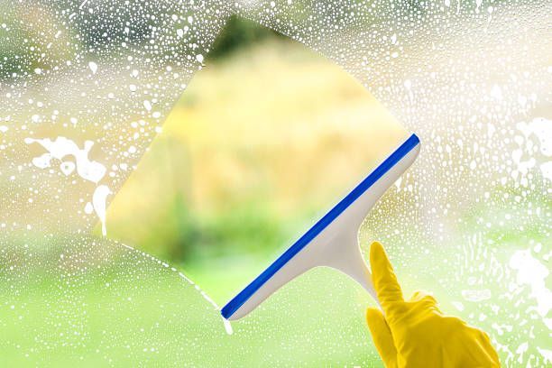 A person is cleaning a window with a squeegee.